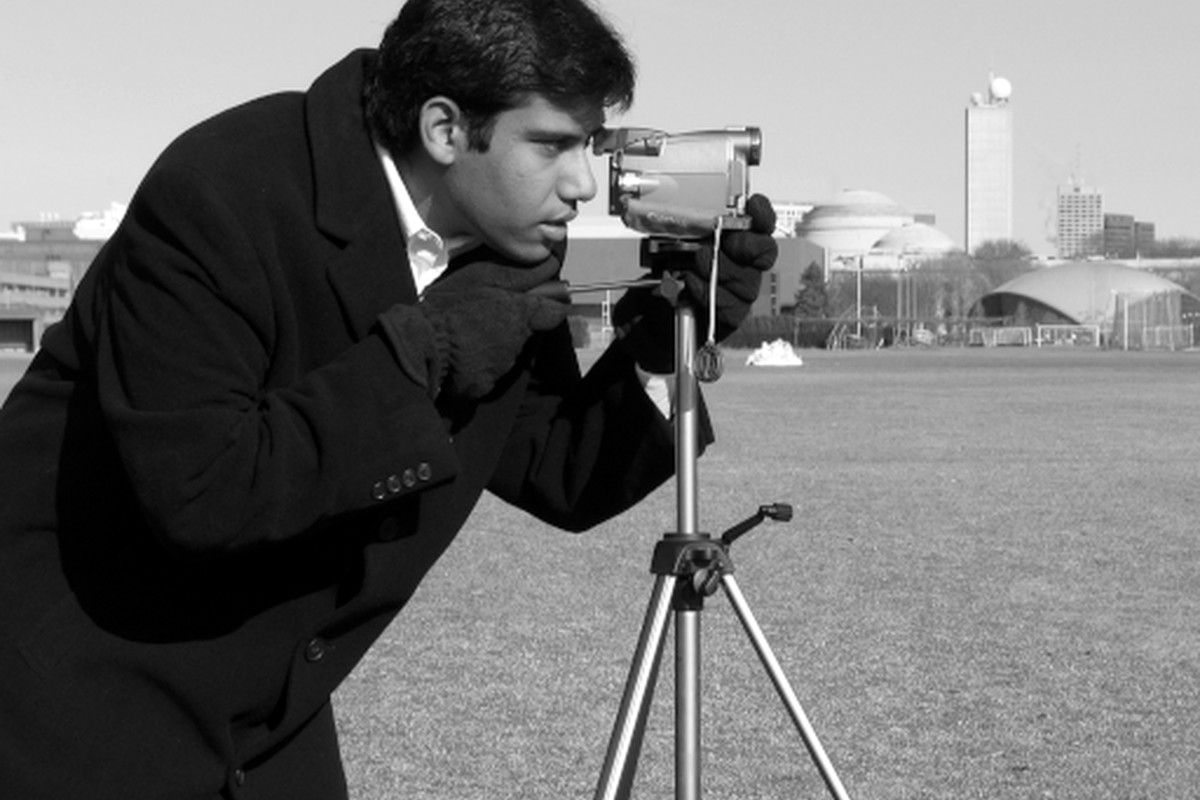 A photographer using a camera on a tripod outdoors.