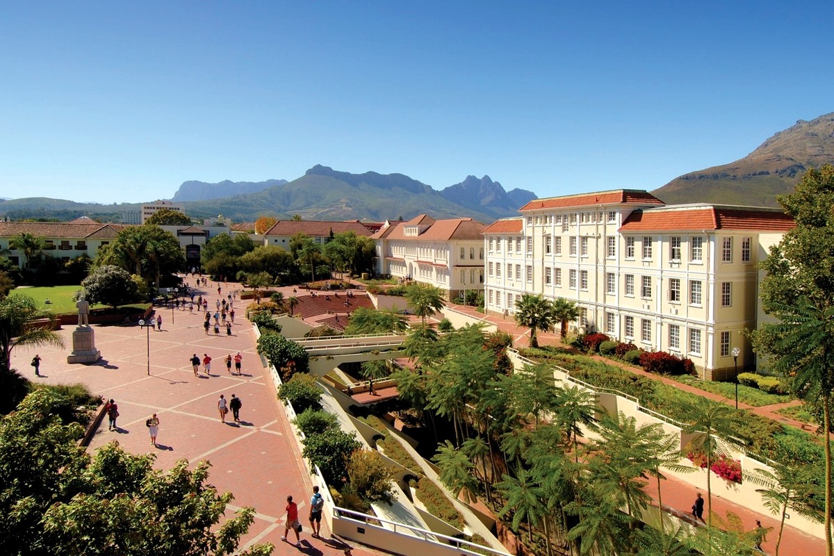 A landscaped courtyard with paths, buildings, trees, and mountains in the distance.
